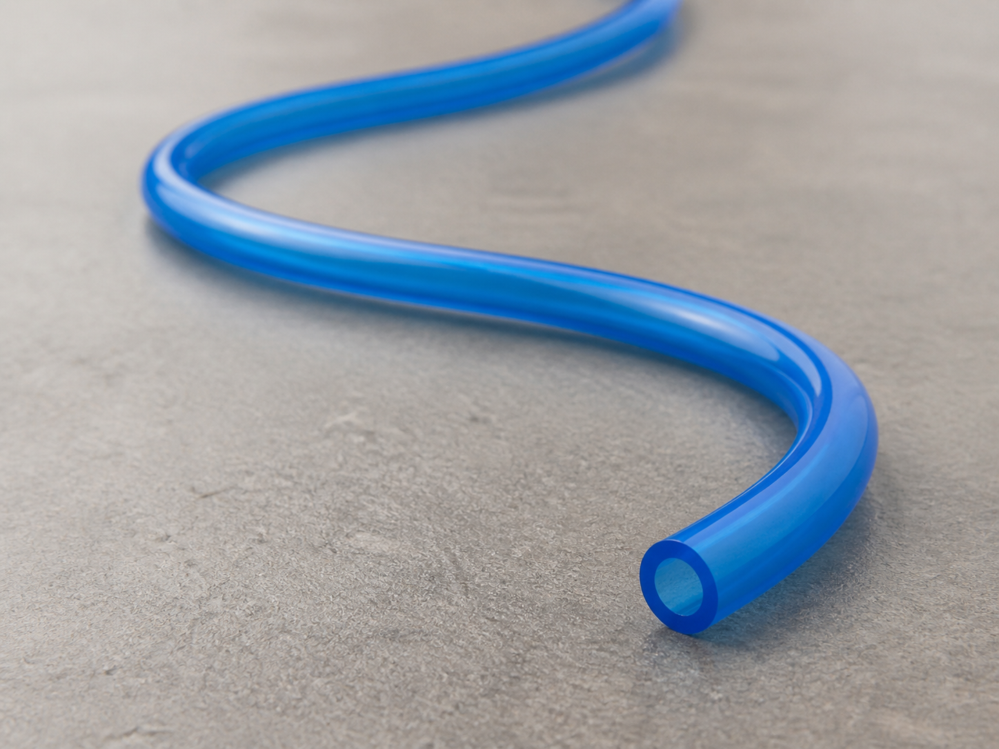 Blue HOLID PU pneumatic tube arranged in a broad S curve on a warm gray studio surface